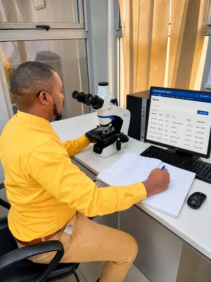 Valentine Golden Ghanem - At the laboratory desk, yellow shirt, reviewing the Lab Information System's sample list.