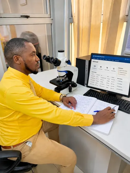 Valentine Golden Ghanem - At the laboratory desk, yellow shirt, reviewing the Lab Information System's dashboard.