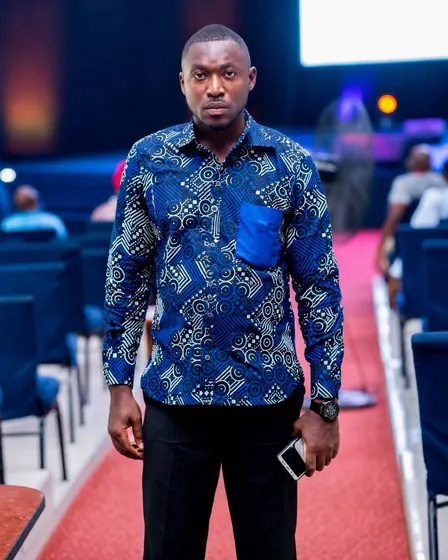 Valentine Golden Ghanem - Portrait in an event hall, blue patterned shirt.