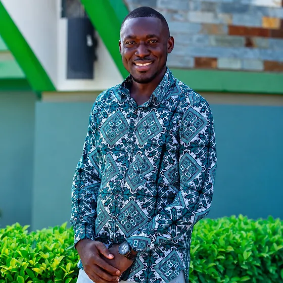 Valentine Golden Ghanem - Outdoor portrait, teal patterned shirt, green shrubs behind him.