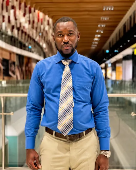 Valentine Golden Ghanem - Portrait in a mall hallway, blue shirt.