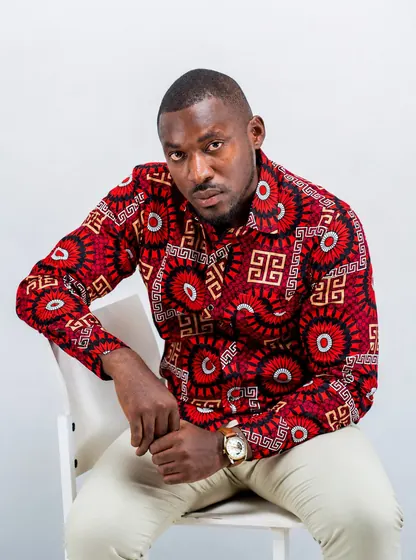 Valentine Golden Ghanem - Studio portrait, seated, red patterned shirt.